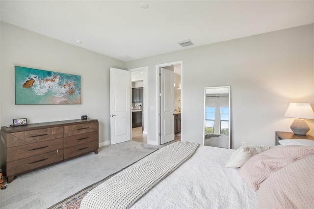 bedroom featuring baseboards, ensuite bath, visible vents, and light colored carpet