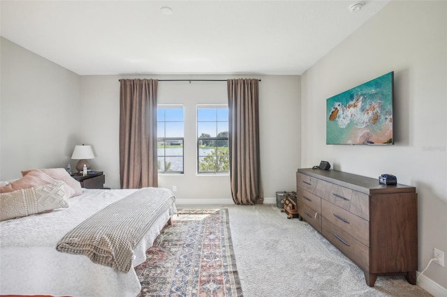 bedroom with light colored carpet and baseboards