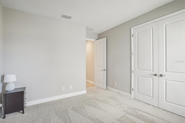 unfurnished bedroom with a closet, carpet, visible vents, and baseboards