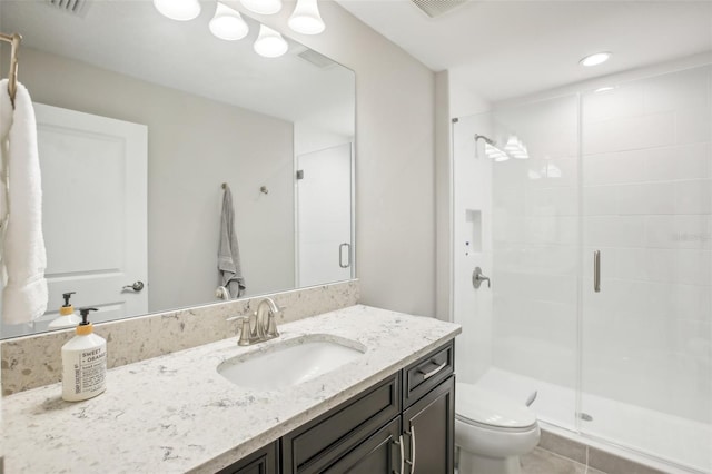 bathroom featuring a shower with door, vanity, toilet, and tile patterned floors