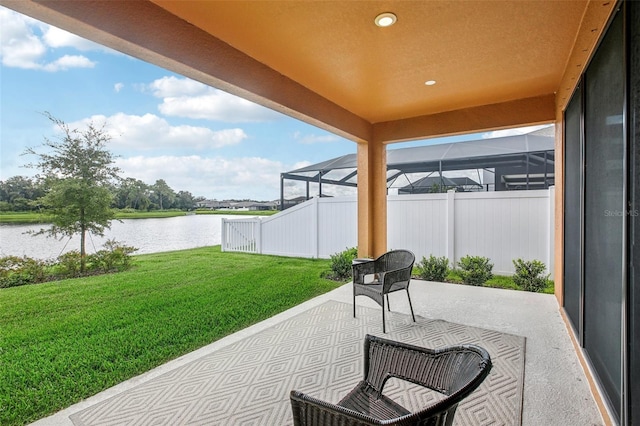 view of patio / terrace featuring a lanai, a water view, and fence