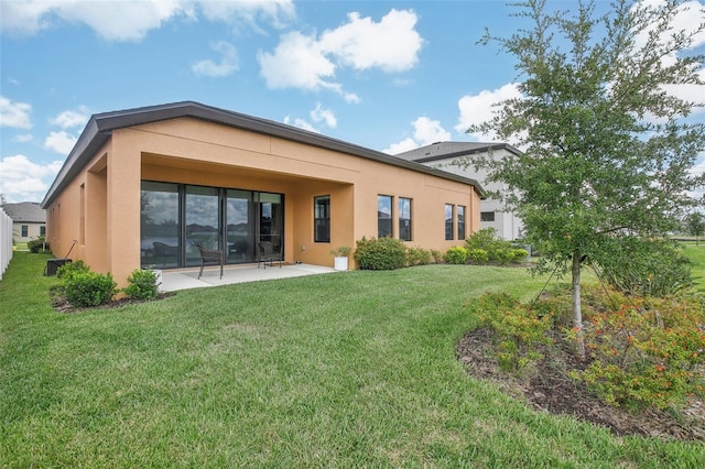 rear view of house with a lawn, a patio area, and stucco siding