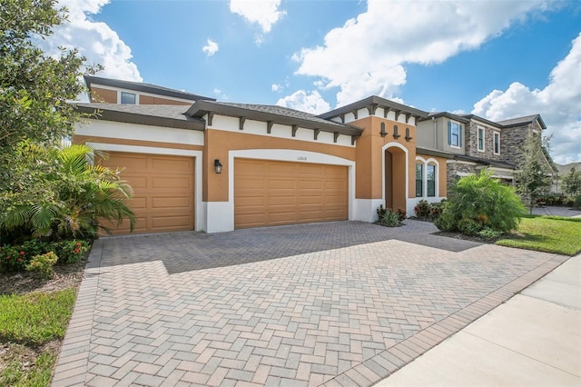 view of front of house with a garage, decorative driveway, and stucco siding