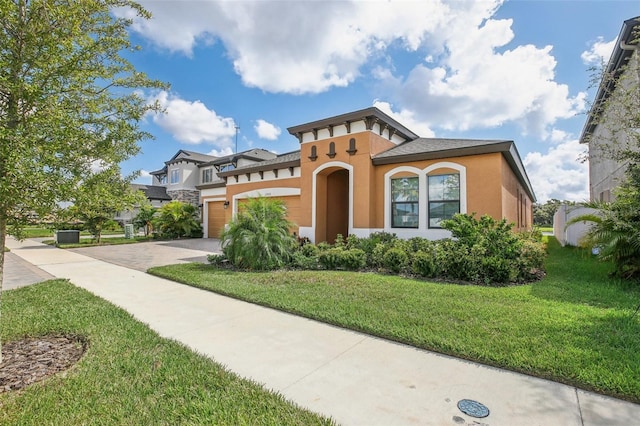 mediterranean / spanish house featuring a front lawn, decorative driveway, an attached garage, and stucco siding
