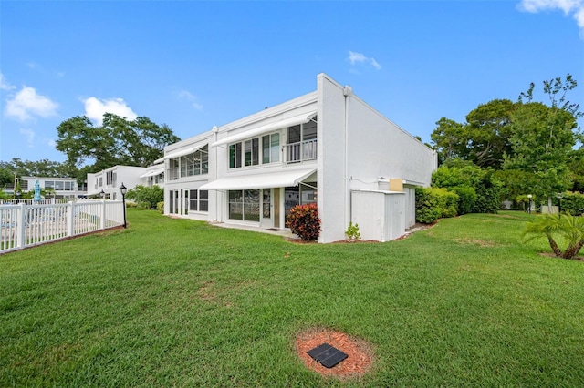 rear view of property featuring a yard, stucco siding, and fence