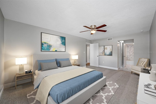 carpeted bedroom with ensuite bath, visible vents, a textured ceiling, and baseboards