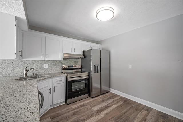 kitchen with under cabinet range hood, wood finished floors, white cabinets, stainless steel appliances, and a sink