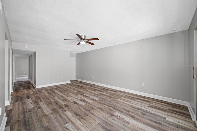 empty room with baseboards, a textured ceiling, wood finished floors, and a ceiling fan