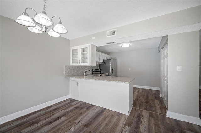 kitchen with visible vents, a peninsula, white cabinets, glass insert cabinets, and appliances with stainless steel finishes