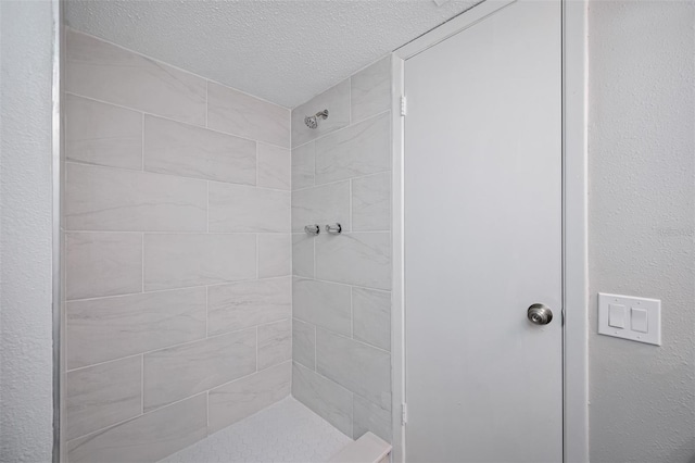 bathroom featuring a tile shower and a textured ceiling