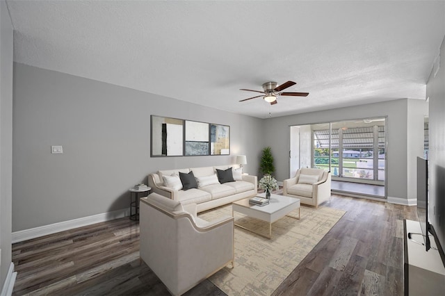 living room featuring baseboards, wood finished floors, a textured ceiling, and ceiling fan