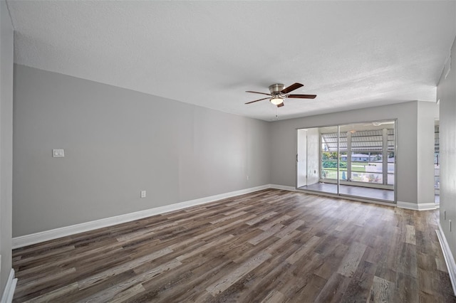 spare room featuring baseboards, a textured ceiling, ceiling fan, and dark wood-style flooring