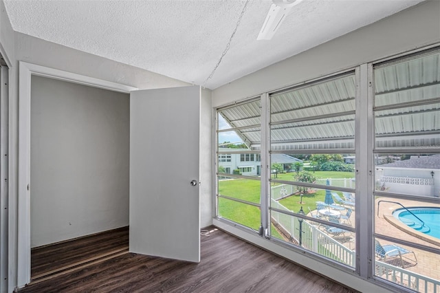 spare room with lofted ceiling, wood finished floors, and a textured ceiling