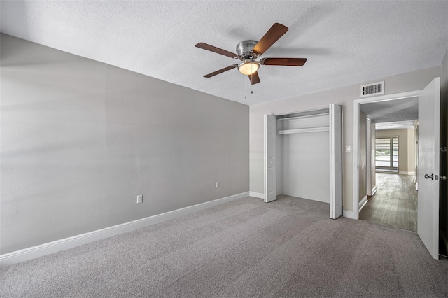 unfurnished bedroom with visible vents, a textured ceiling, a closet, and carpet flooring