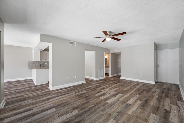 unfurnished living room featuring visible vents, baseboards, dark wood-style floors, and ceiling fan