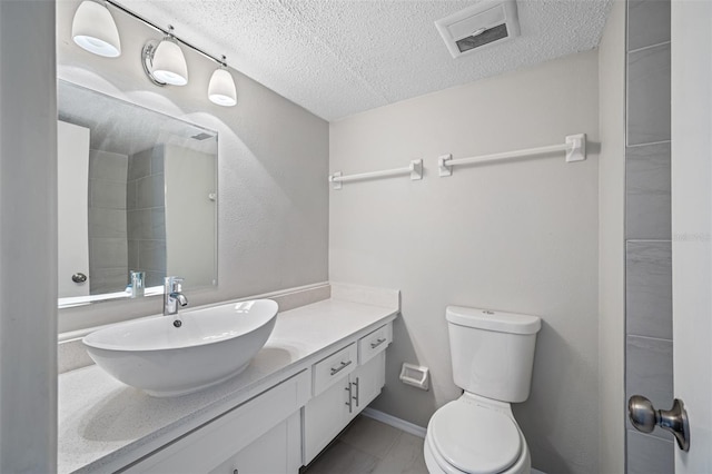 bathroom with visible vents, toilet, a textured ceiling, baseboards, and vanity