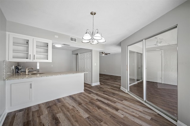 kitchen with visible vents, a sink, dark wood finished floors, white cabinetry, and glass insert cabinets