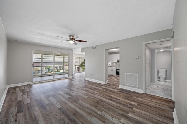 unfurnished living room featuring dark wood-style floors, visible vents, and ceiling fan