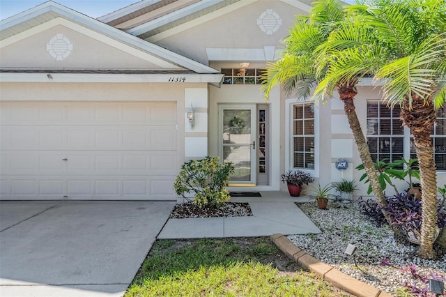 view of exterior entry featuring a garage, concrete driveway, and stucco siding