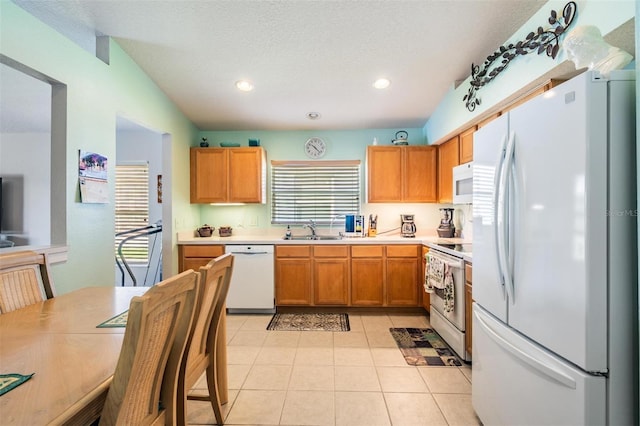 kitchen with light tile patterned floors, recessed lighting, white appliances, a sink, and light countertops