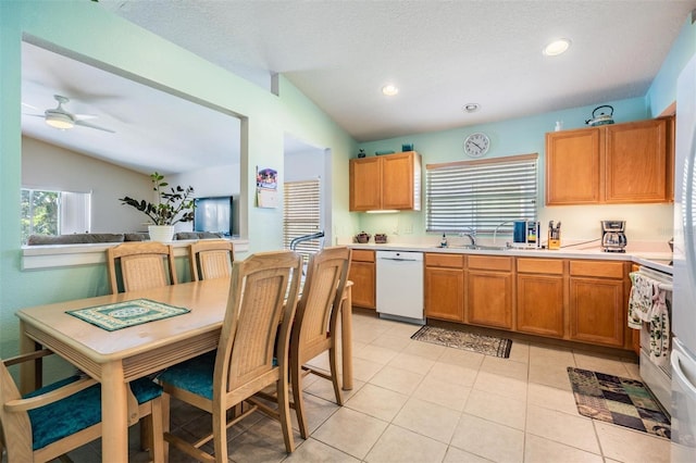 kitchen with lofted ceiling, light tile patterned floors, ceiling fan, and white dishwasher