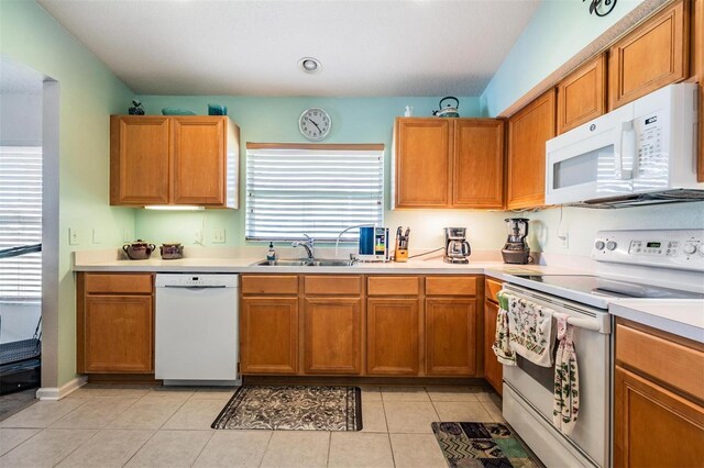 kitchen with white appliances, light tile patterned flooring, and sink