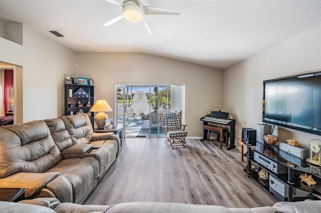 living room featuring ceiling fan, vaulted ceiling, a textured ceiling, and light hardwood / wood-style flooring