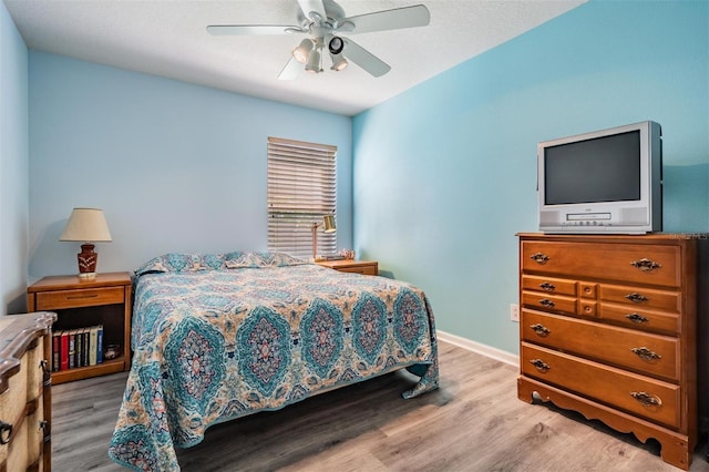 bedroom featuring ceiling fan, baseboards, and wood finished floors