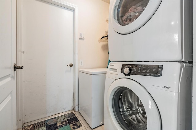 washroom featuring laundry area, stacked washer and dryer, and light tile patterned flooring