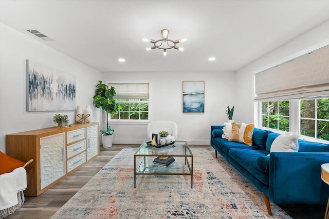 living room with a wealth of natural light, a notable chandelier, and hardwood / wood-style floors