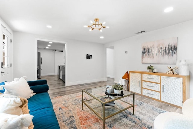 living room with an inviting chandelier and light wood-type flooring