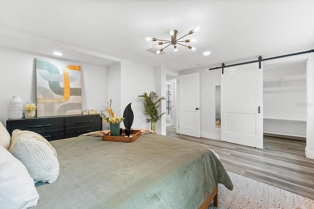 bedroom featuring a spacious closet, a closet, light hardwood / wood-style flooring, and a barn door