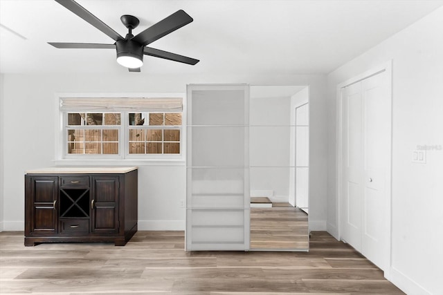 bar with light hardwood / wood-style flooring, ceiling fan, and dark brown cabinets