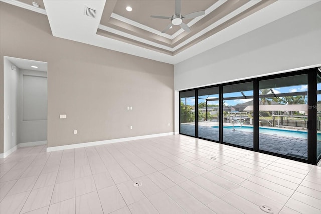 unfurnished room with ceiling fan, a raised ceiling, crown molding, a towering ceiling, and light tile patterned floors