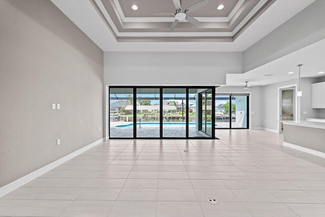 empty room featuring light tile patterned floors, a towering ceiling, ceiling fan, and ornamental molding