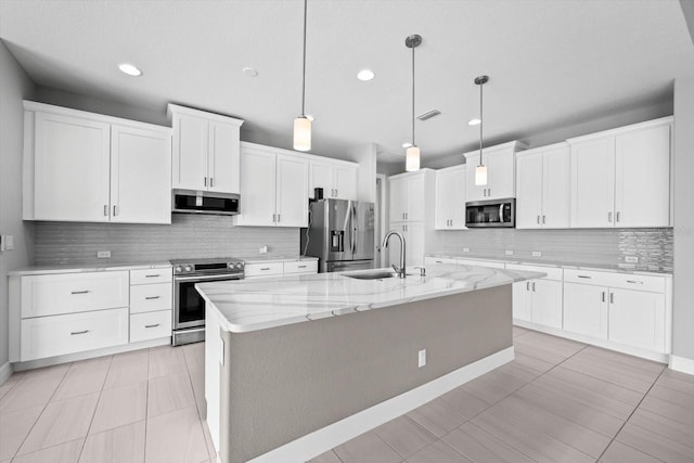 kitchen featuring appliances with stainless steel finishes, sink, a center island with sink, decorative light fixtures, and white cabinetry