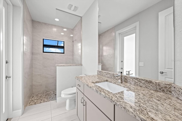 bathroom with tile patterned floors, vanity, toilet, and tiled shower