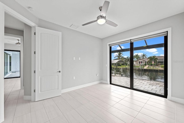 tiled spare room featuring ceiling fan and a water view