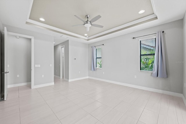 spare room with a raised ceiling, ceiling fan, light tile patterned floors, and ornamental molding