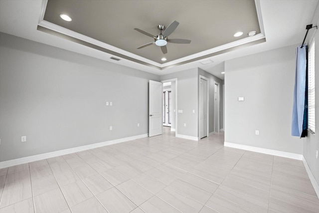 spare room with a tray ceiling, ceiling fan, and light tile patterned flooring