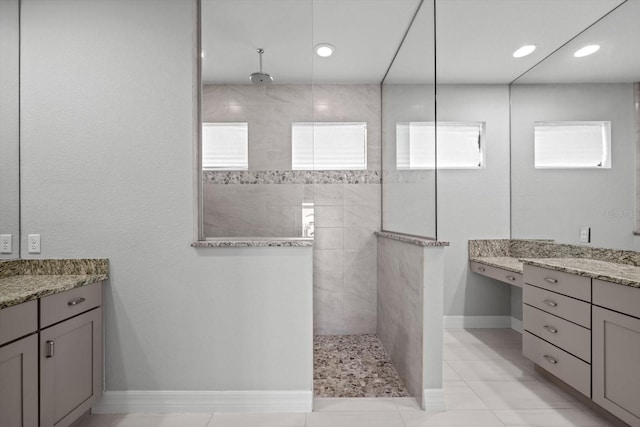 bathroom with tile patterned flooring, vanity, and tiled shower