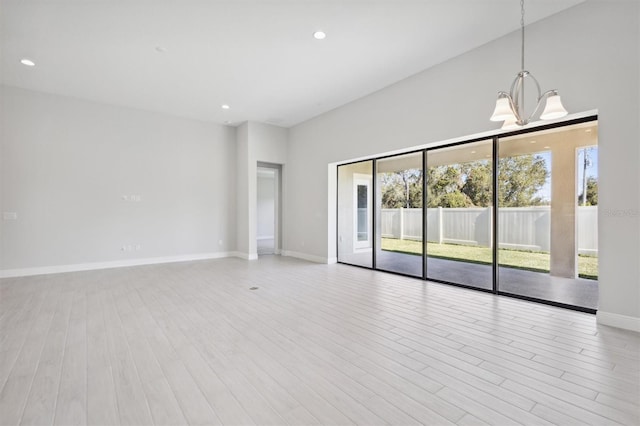 empty room featuring a chandelier and light wood-type flooring