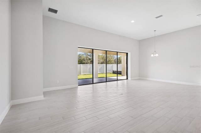 spare room with an inviting chandelier and light hardwood / wood-style flooring