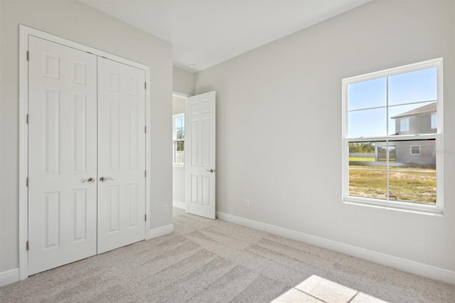 unfurnished bedroom featuring light carpet and a closet