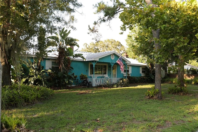 ranch-style house featuring covered porch and a front yard