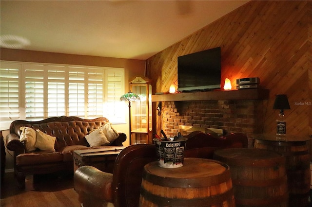 living room with hardwood / wood-style flooring, a brick fireplace, and wooden walls