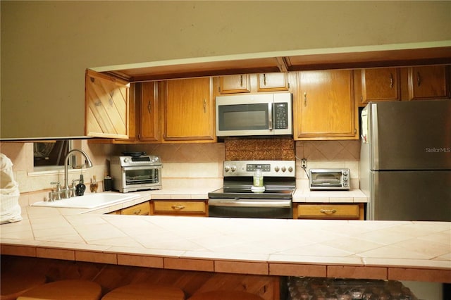 kitchen featuring tile counters, a breakfast bar, stainless steel appliances, and sink