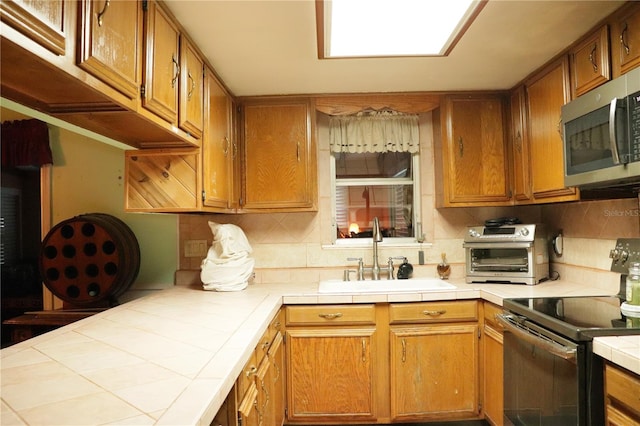 kitchen with stainless steel appliances, sink, tile countertops, and decorative backsplash