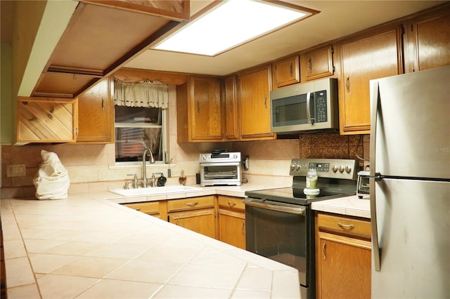 kitchen with backsplash, stainless steel appliances, sink, and tile countertops