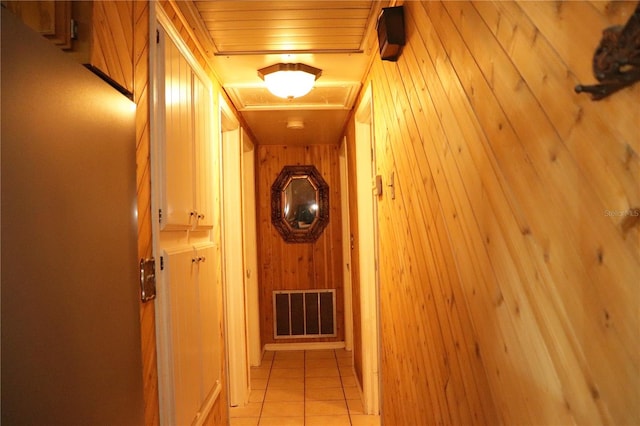 corridor featuring light tile patterned floors and wooden walls